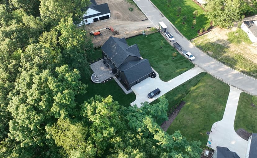 Aerial view of a modern home surrounded by lush greenery and landscaped yard.