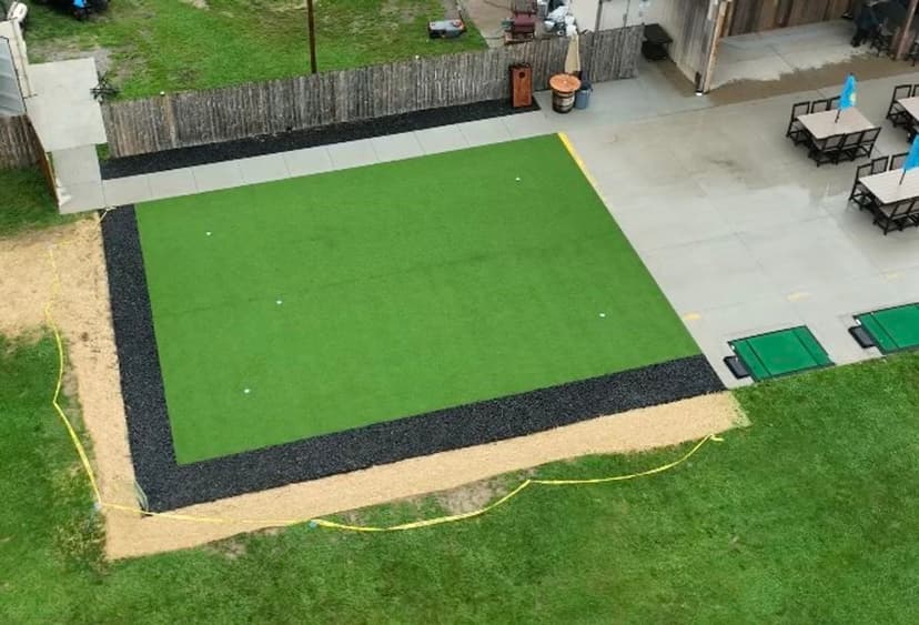 Aerial view of a backyard putting green surrounded by gravel and concrete patio area.