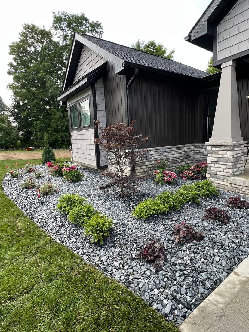 Modern home exterior with landscaped gravel garden and colorful flower beds.