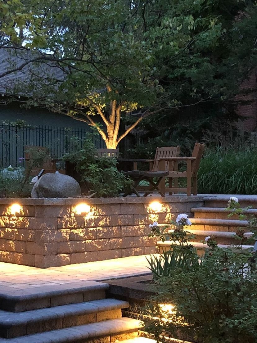 Serene garden at dusk with stone steps, soft lighting, and a cozy seating area.