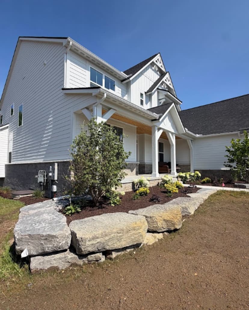 Modern home exterior with landscaped front yard and stone pathways under clear blue sky.