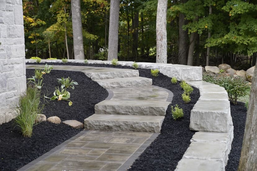 Winding stone pathway surrounded by greenery and mulch, nestled in a serene garden setting.