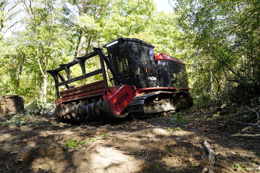 Reclaiming machine in wooded area, clearing land and preparing for development.